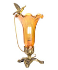 Amber lily glass lamp with a decorative soaring hummingbird bird on a dark and light bronze 3 leaf base.
