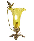 Yellow lily glass lamp with a decorative soaring hummingbird bird on a dark and light bronze 3 leaf base.